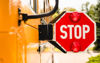 Side view of a school bus with an extended stop sign and two red lights.