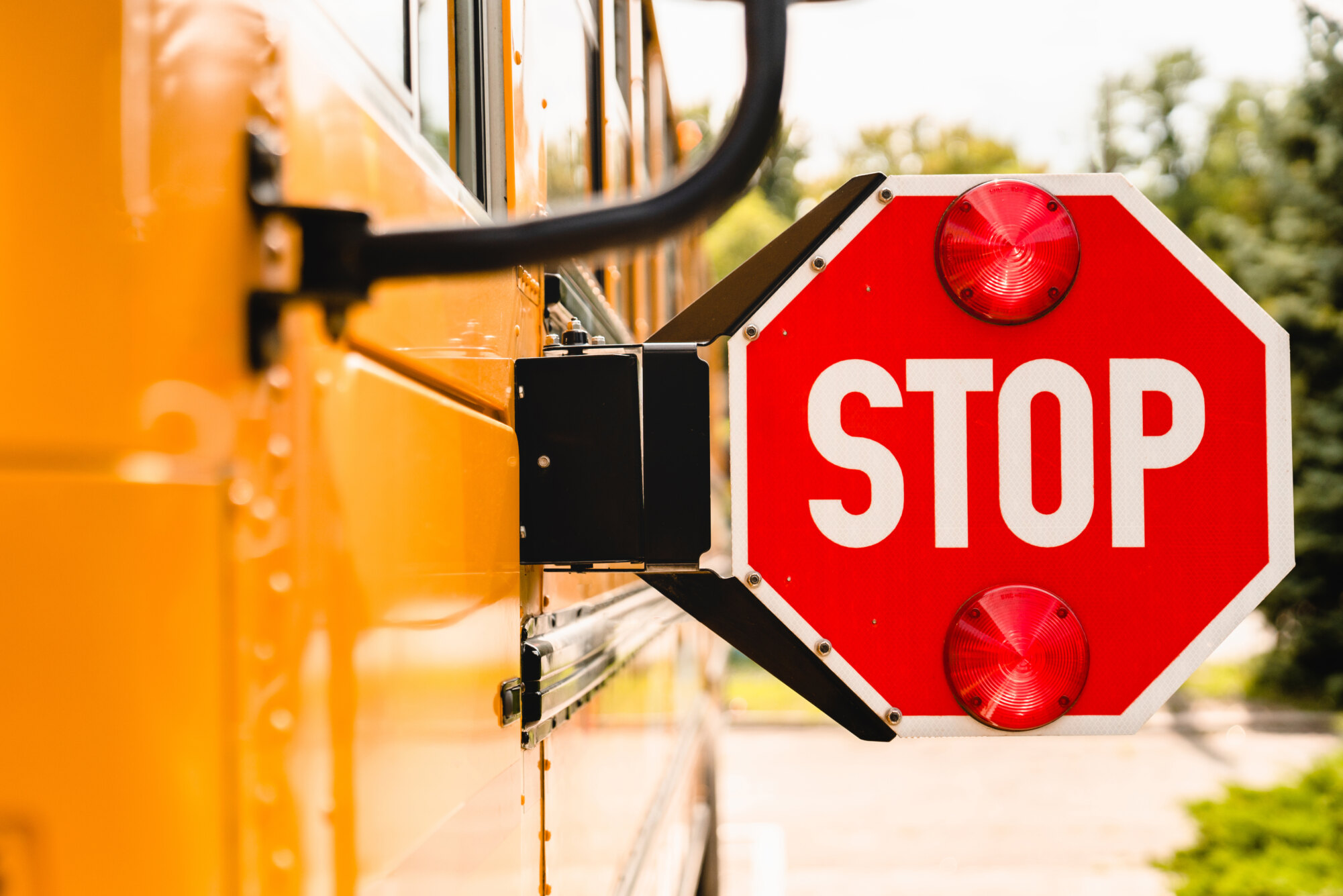 Side view of a school bus with an extended stop sign and two red lights.