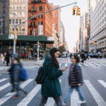 Woman crossing busy city street while looking at phone.